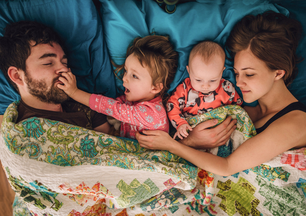 Family of four cuddling in bed 